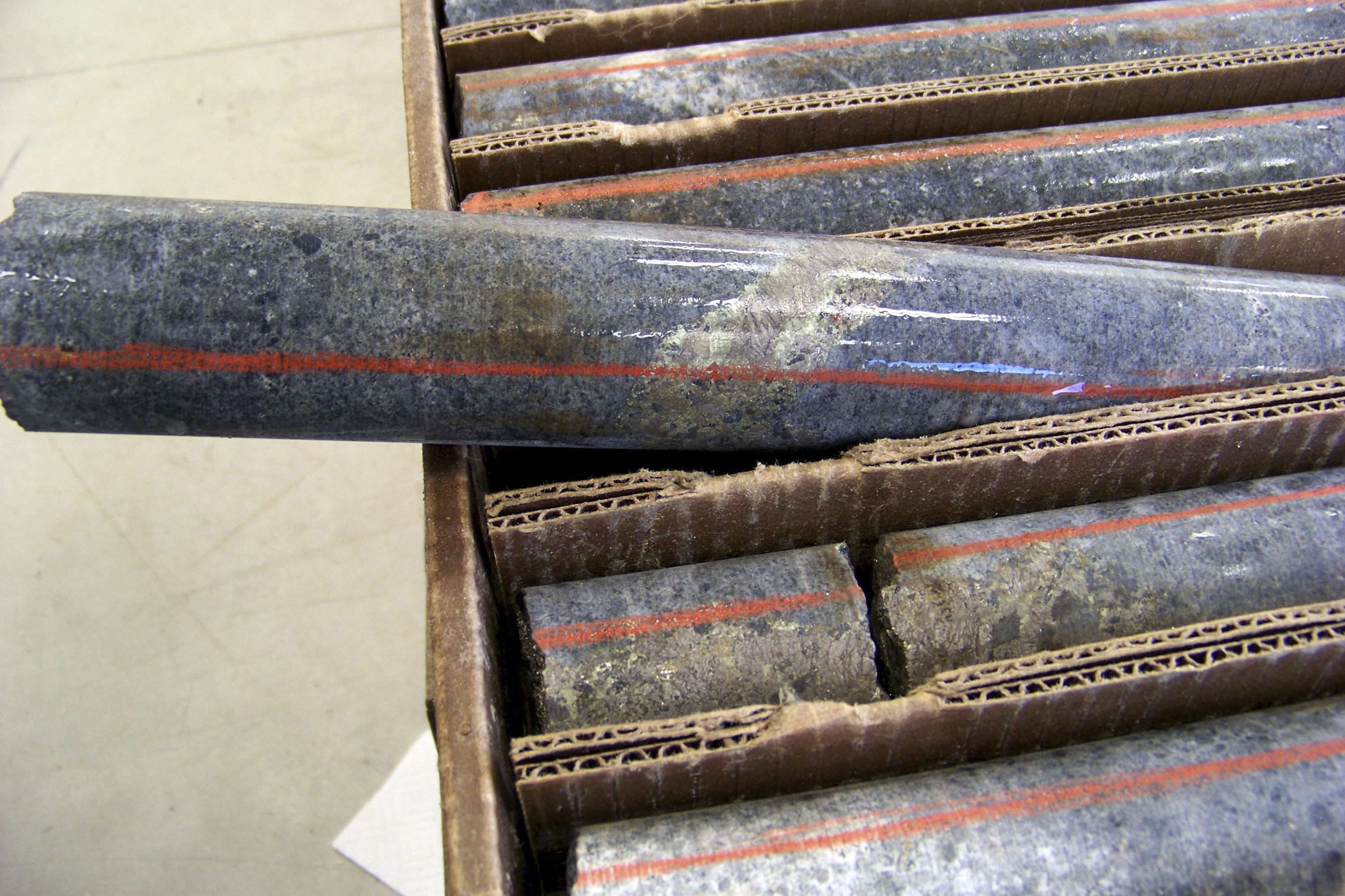 A box of core samples showing a band of shiny minerals containing copper, nickel and precious metals. A box of core samples showing a band of shiny minerals containing copper, nickel and precious metals.