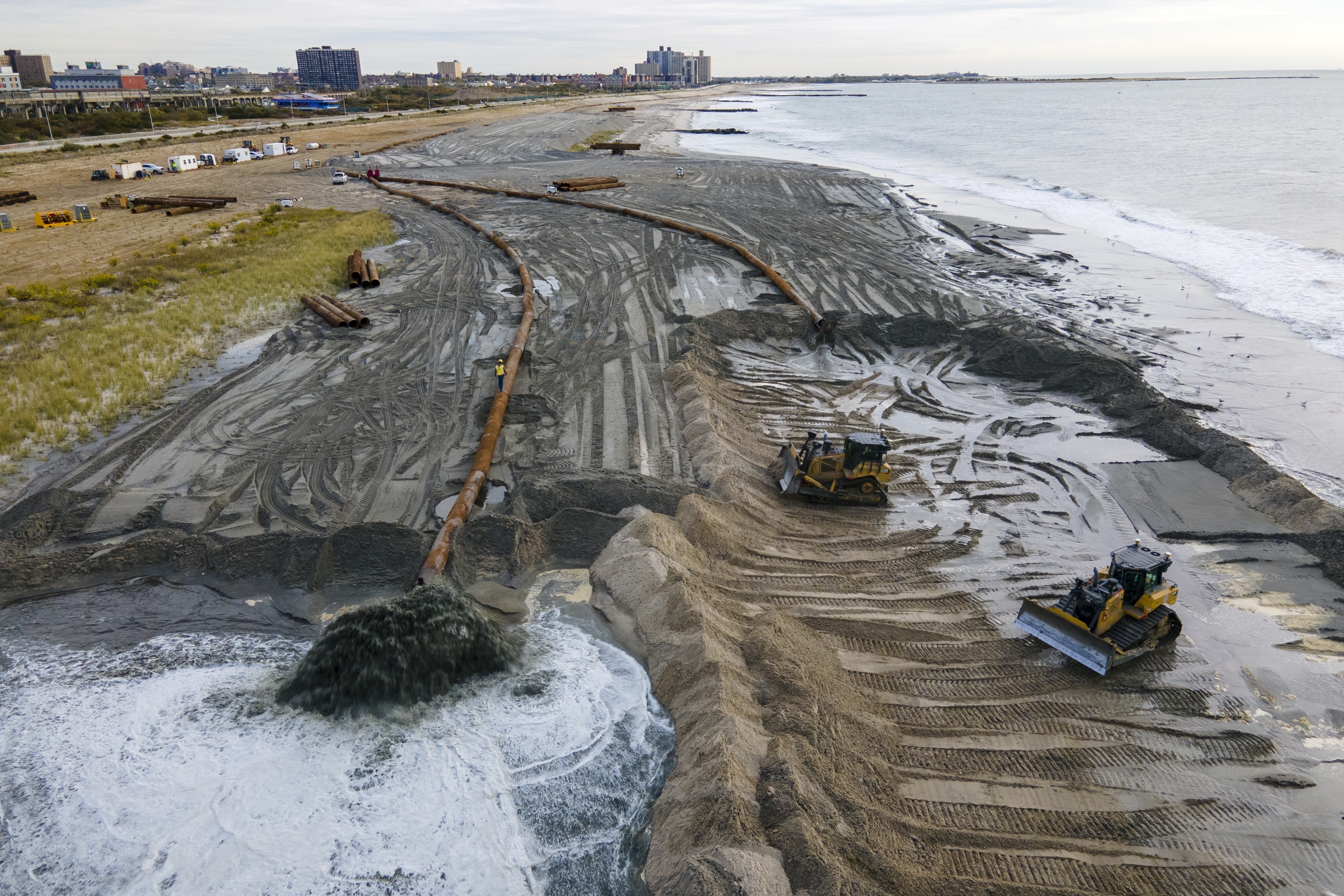 Tractors spread sand on a beach in New York. Tractors spread sand on a beach in New York.